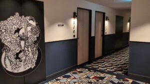 Contemporary hotel corridor in Japan with patterned carpet and minimalist decor.