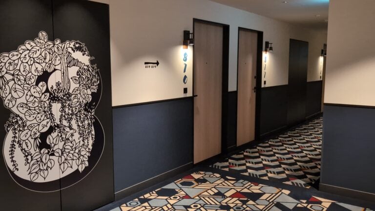 Contemporary hotel corridor in Japan with patterned carpet and minimalist decor.