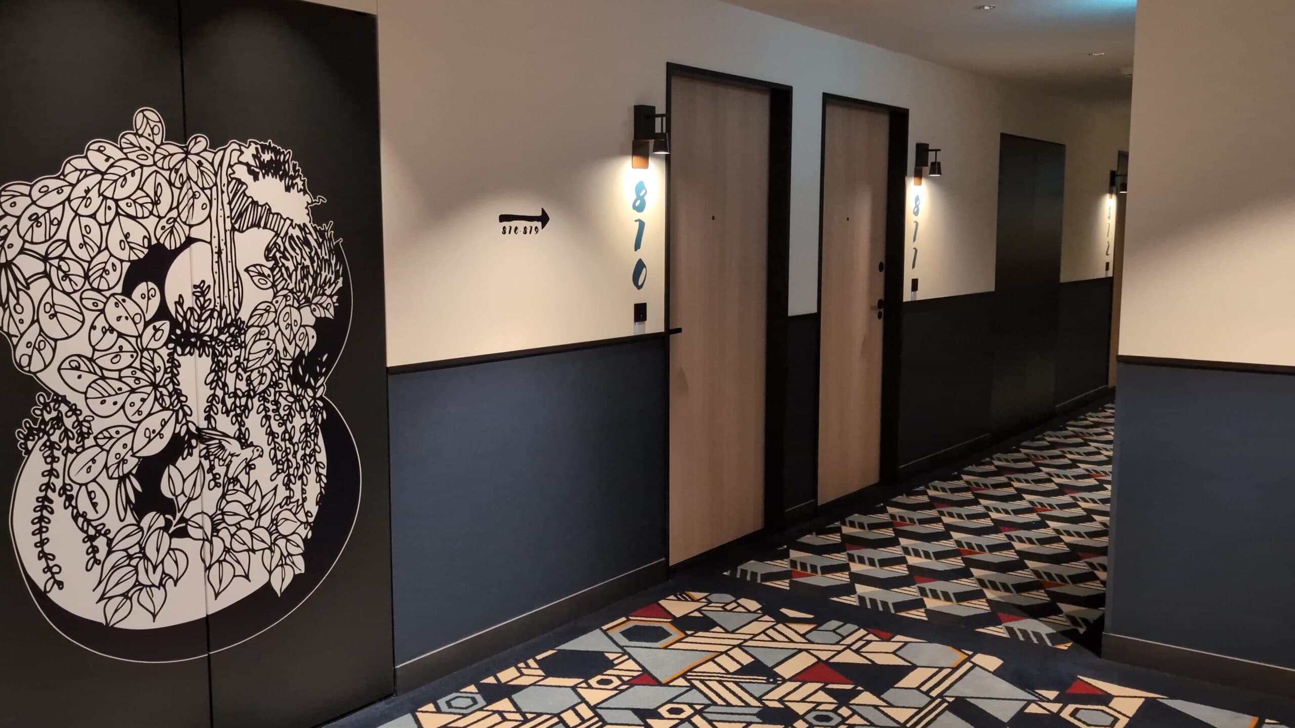 Contemporary hotel corridor in Japan with patterned carpet and minimalist decor.