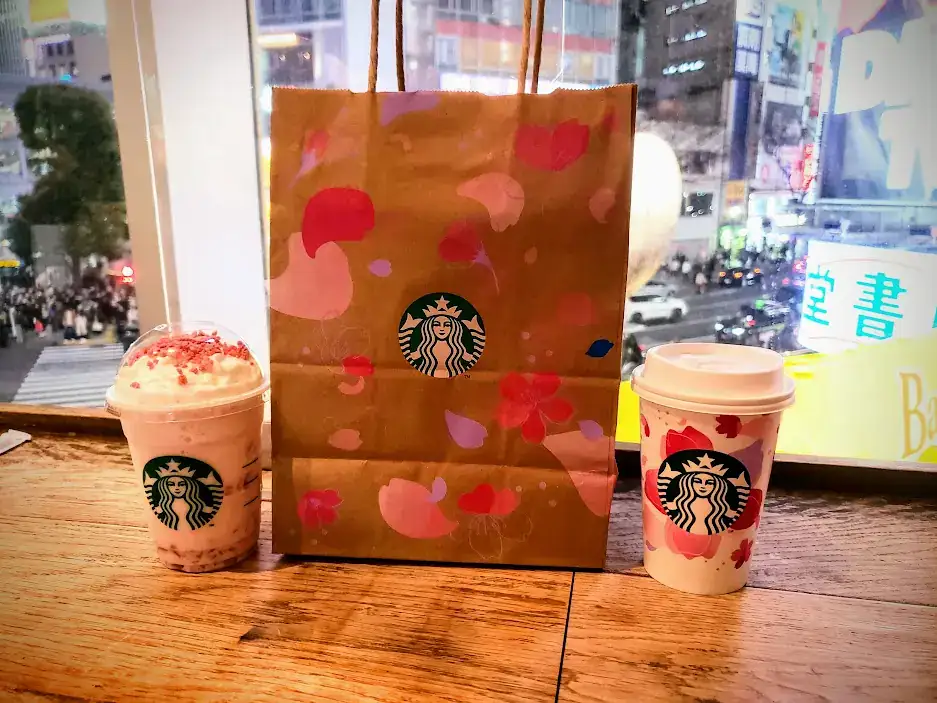 A starbucks bag and two drinks at a shop in Shibuya crossing