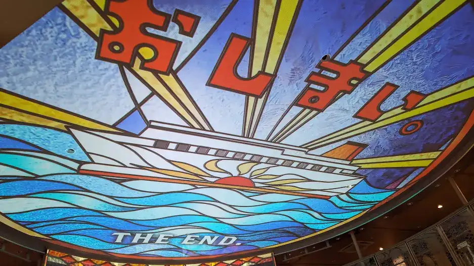Digital stained glass ceiling with a ship, sunrise, and blue waves. Bold Japanese text and "THE END." in the foreground, creating a vibrant scene.