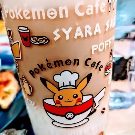 Glass with Pokémon Cafe designs, featuring Pikachu in chef hat. Text includes Pokémon Cafe and images of drinks. Bright and colorful.