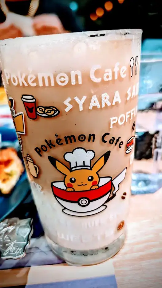 Glass with Pokémon Cafe designs, featuring Pikachu in chef hat. Text includes Pokémon Cafe and images of drinks. Bright and colorful.