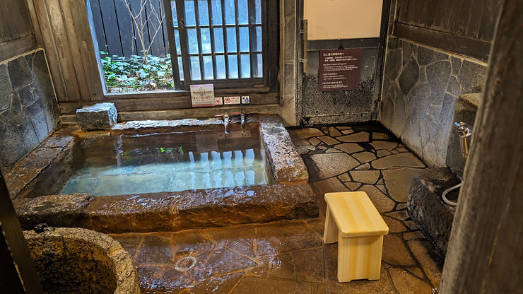 Indoor Japanese onsen with stone bath and wooden stool in Beppu, Japan.