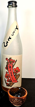 Frosted umeshu plum wine bottle with black text label, red floral design, and kanji from Kyoto, Japan. Brown textured glass cup in front. Simple, clean background.