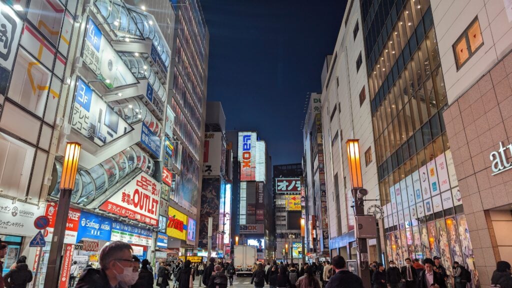 Vibrant Tokyo street scene at night with neon lights and busy pedestrians.