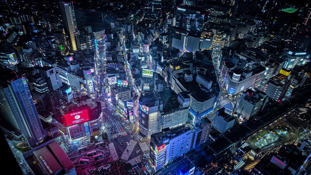 Shibuya Crossing street intersection at night with glowing neon billboards in Tokyo Japan