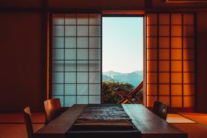A serene Japanese room featuring shoji screens and a mountain view, illuminated by warm lighting.
