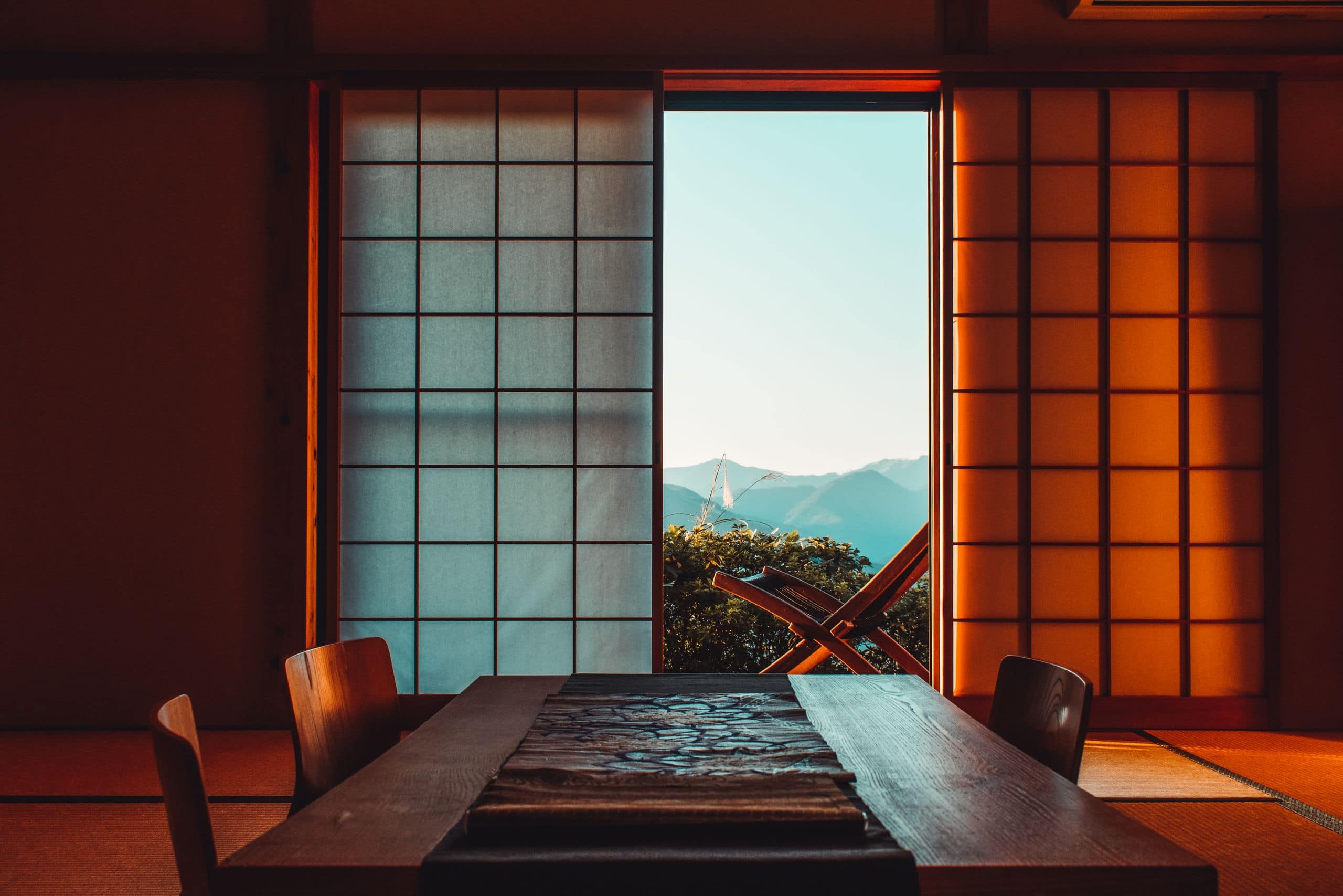 A serene Japanese room featuring shoji screens and a mountain view, illuminated by warm lighting.