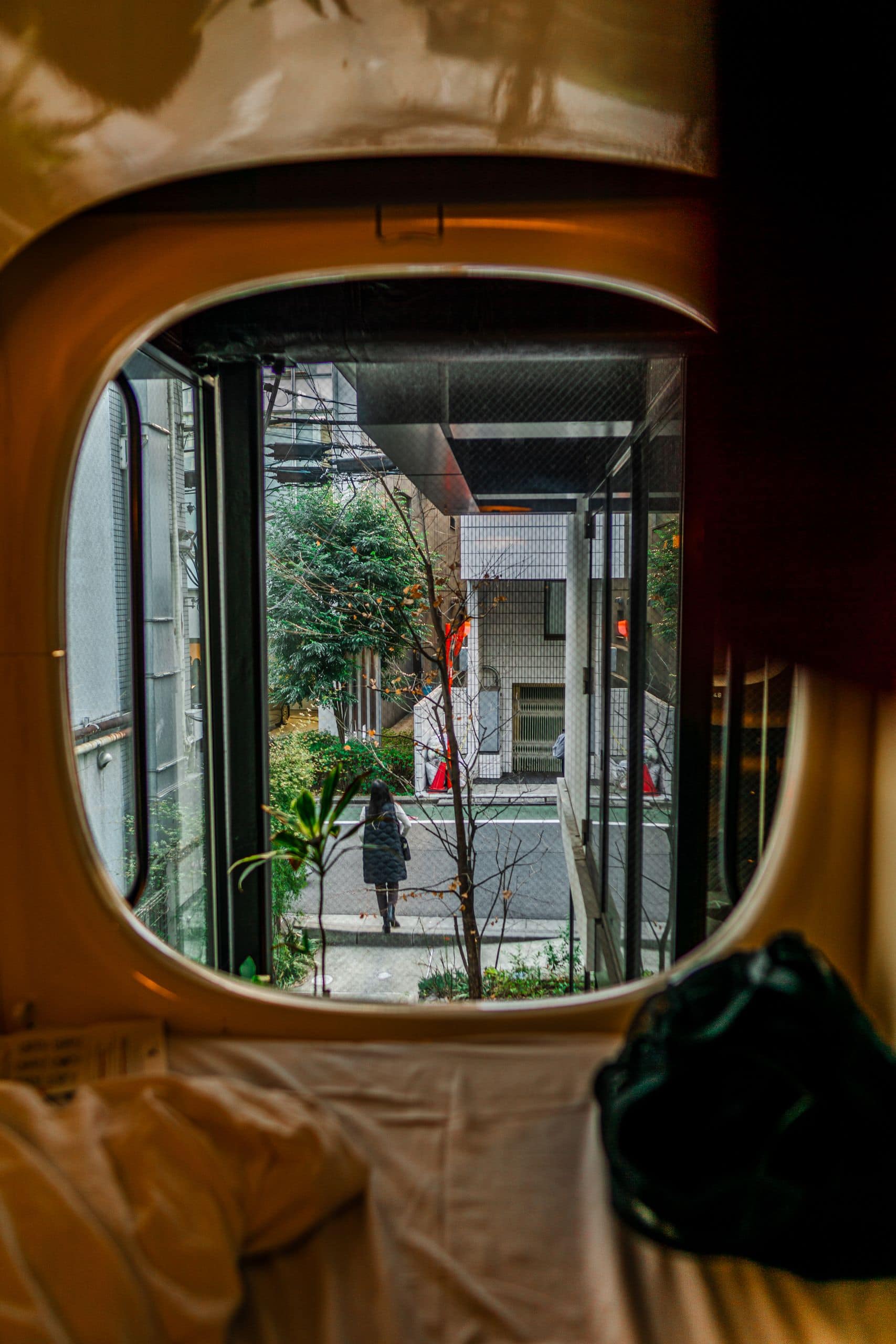 A view from a capsule hotel window revealing a modern city street outside.