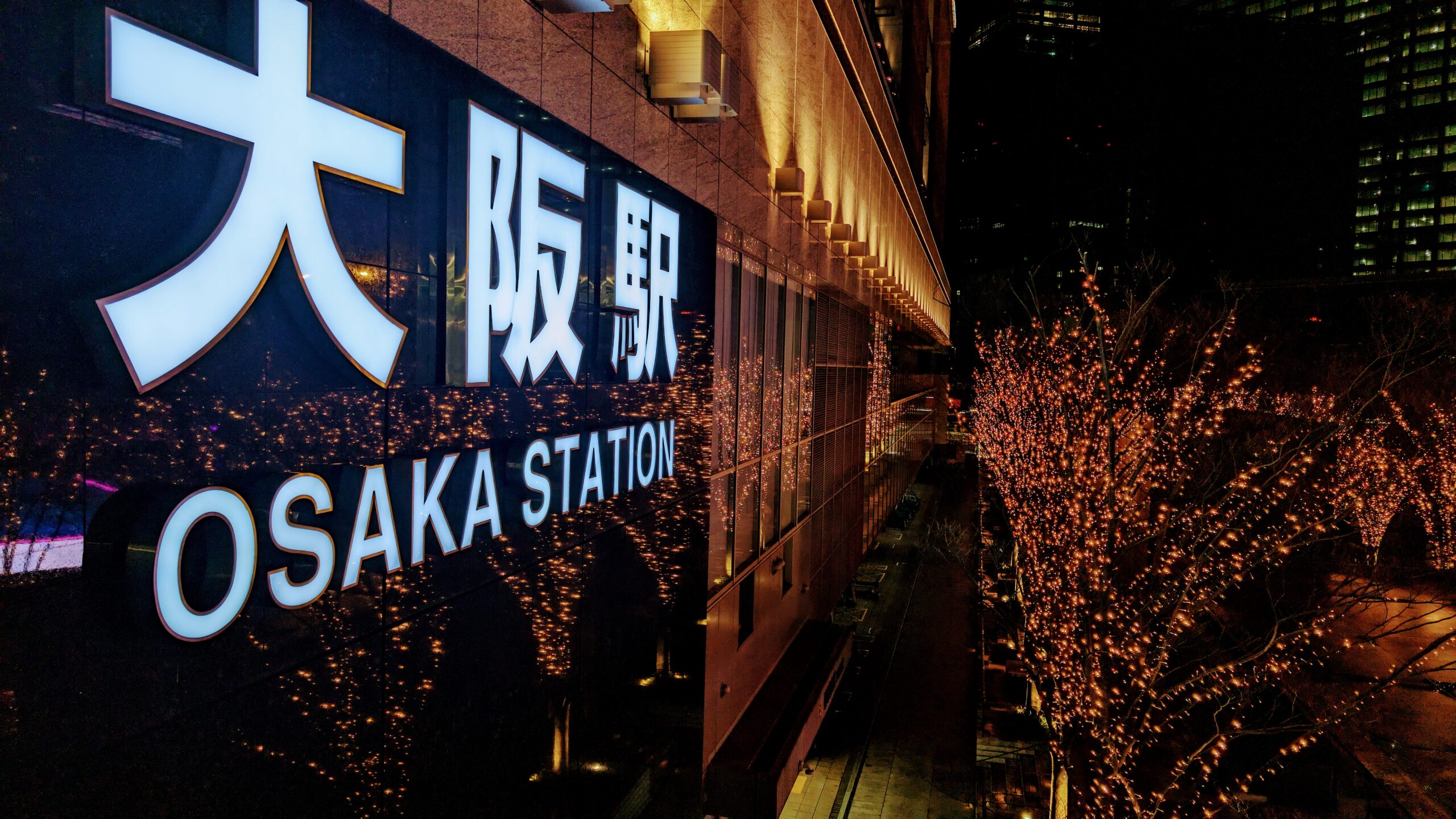 Night view of Osaka Station with illuminated trees and signage in Kansai Area.