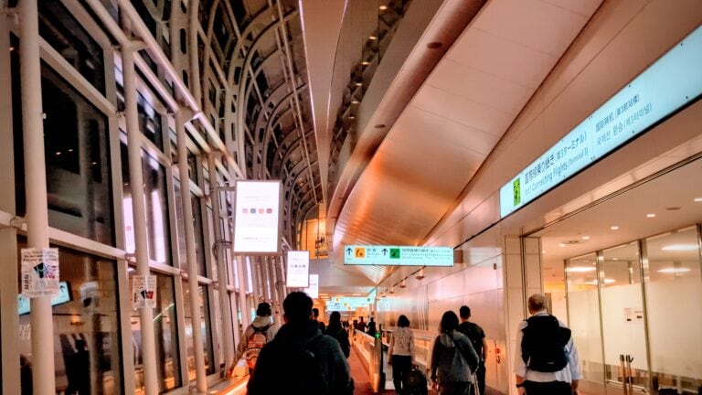 People walking through a sleek, modern airport terminal in Japan at night.